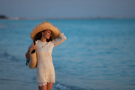 悠闲的现代中年妇女站在海滩上日落