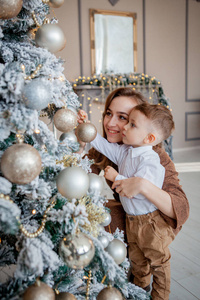小男孩和妈妈为圣诞节装饰一棵圣诞树