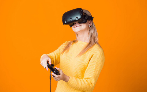 电脑游戏机使用虚拟现实。一个戴着虚拟现实头盔，手里拿着游戏板的年轻女子