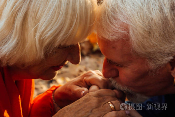 一个幸福的老人亲吻妻子的手的特写肖像一对幸福的夫妇正在公园里的