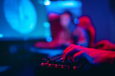 模糊的背景电脑，键盘，蓝色和红色的灯光。游戏玩家玩锦标赛的概念电子竞技竞技场