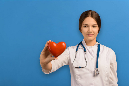 美女女性心脏病专家看着镜头,在蓝色背景下微笑,展示心脏健康护理的