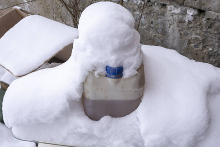 雪地上的液体罐。白天霜冻中的液体。雪堆