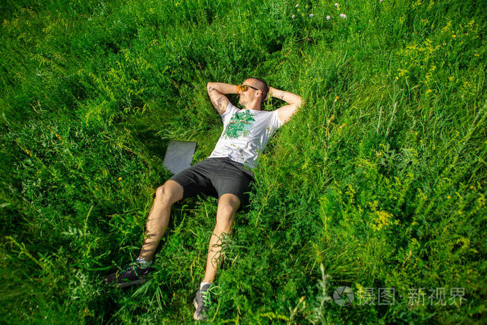 自由职业者躺在草地上的草地上带着笔记本电脑