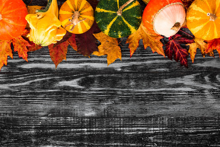 感恩节或万圣节背景。秋季作文。黑色木桌上放着落叶的南瓜。平铺