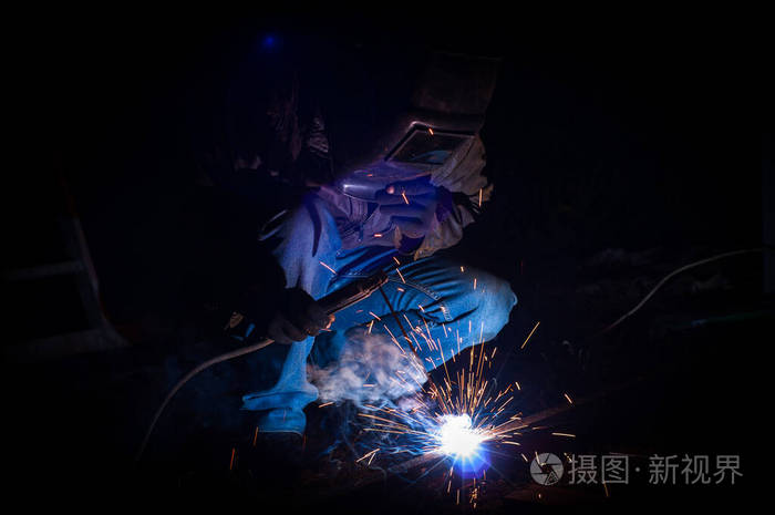 焊工在夜间焊接一个金属车库