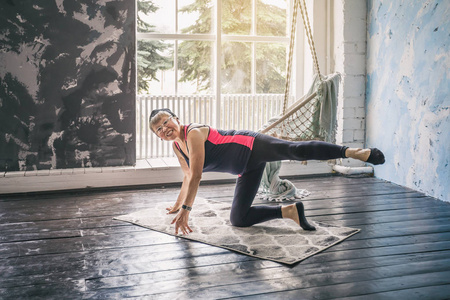 An elderly woman doing gymnastics while at home. The concept of 