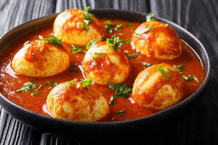 Traditional indian curry eggs served in spicy sauce closeup in 