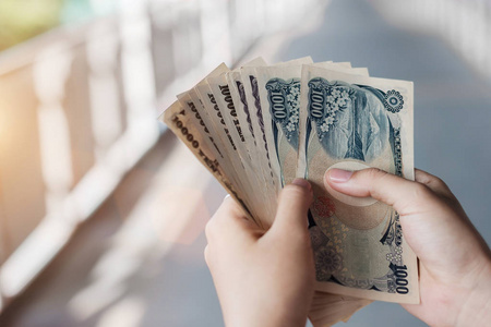 Businessman hand holding Japanese Yen banknote stack. business, 