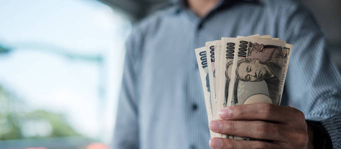 Businessman hand holding Japanese Yen banknote stack. business, 