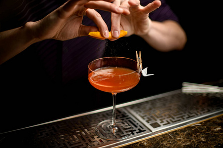 专业调酒师用橙汁喷在装饰有纸飞机的鸡尾酒上