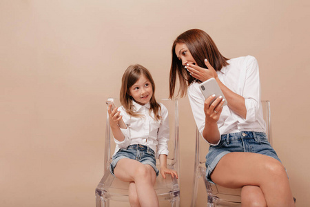 Portrait of pretty woman with little charming girl sitting on ch