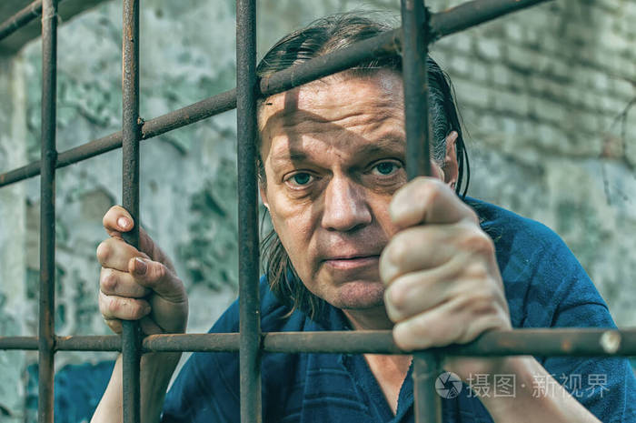 一个沮丧的人把手放在监狱的铁栏上罪魁祸首恶劣的环境尖叫绝望痛苦