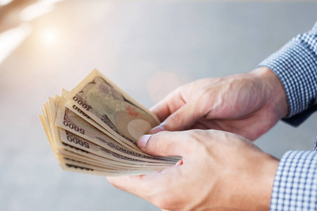 Businessman hand holding Japanese Yen banknote stack. business, 