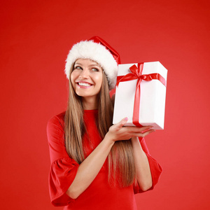 快乐的年轻女子戴着圣诞帽，红色背景上有圣诞礼物