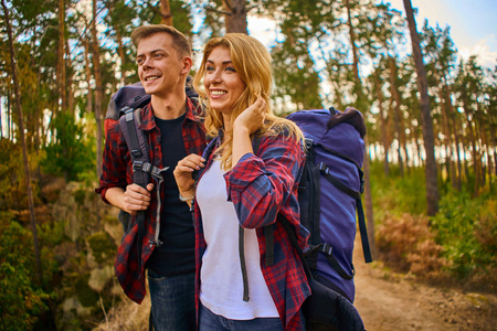 A young man and a woman with backpacks go hiking in the mountain