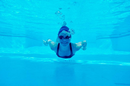 年轻的女孩在游泳池里游泳，看上去像个女人，面带微笑