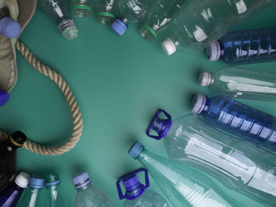 特写一个垃圾袋与空塑料瓶的绿色背景，塑料瓶垃圾回收利用的概念再利用
