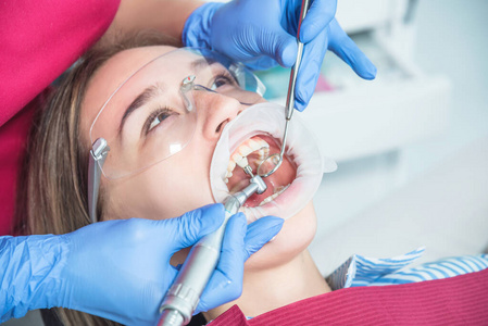 牙医在牙科诊所用牙科设备特写治疗病人。