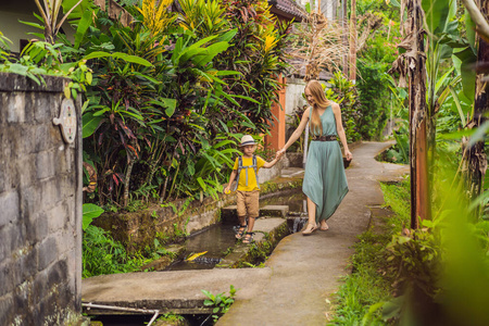 巴厘岛的母子游客沿着乌布狭窄舒适的街道散步。巴厘岛是一个受欢迎的旅游胜地。巴厘岛旅游概念。儿童旅游概念