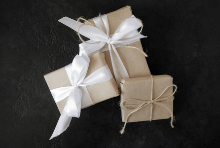  grey gift boxes with white ribbons on black background