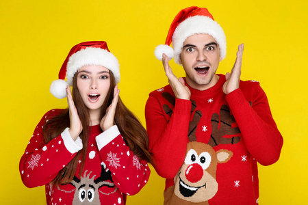 Beautiful man and woman in christmas sweaters and santa hats on 