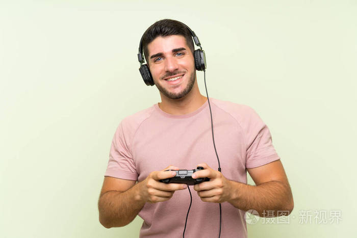 年轻帅哥在孤零零的绿墙上玩游戏机控制器