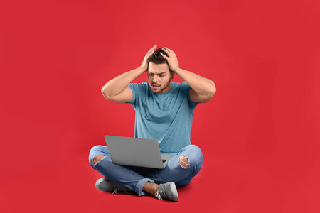 Emotional man with laptop on red background