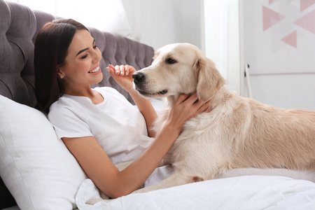 年轻女子和她的金猎犬躺在家里的床上