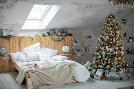一个装饰精美的房子里的圣诞树，树下有圣诞礼物。树立在床边