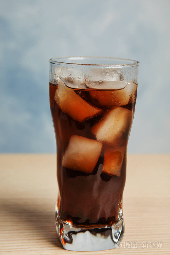 蓝色背景的木制桌子上放着一杯清爽的苏打饮料