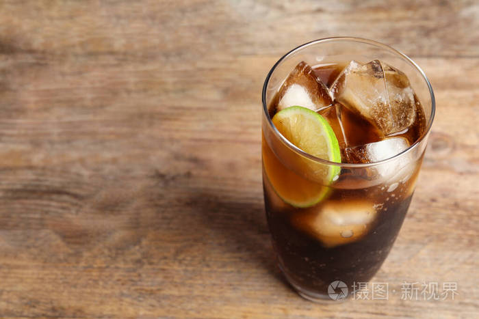 一杯清爽的苏打饮料在木桌上放冰块和酸橙文本空间