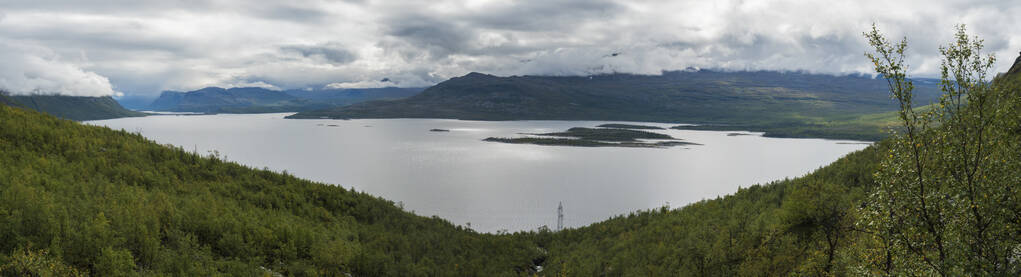 在Kungsleden徒步小道的Akkajaure湖全景，青山和云雾中的桦树林