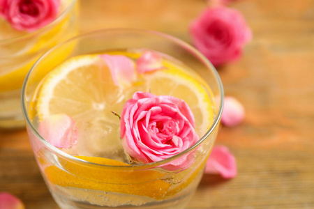 木桌上放着玫瑰的清爽柠檬饮料，特写