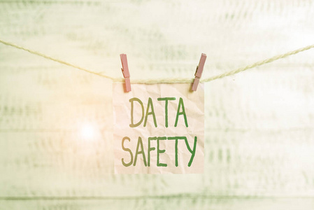 显示数据安全性的概念性手写体。商业照片展示通过确保安全存储衣物防止数据丢失矩形纸夹提醒白木桌子。