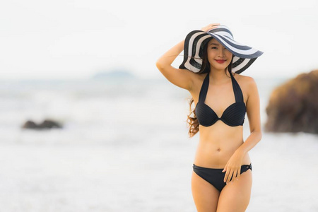 美丽的年轻亚洲女人在海滩上穿着比基尼