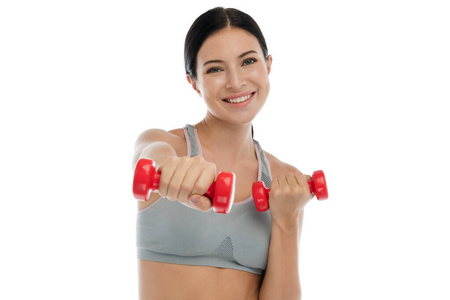 Smiling sporty woman standing and holding dumbbell  isolated on 