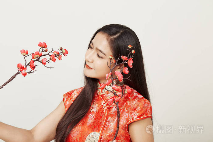 一位身着传统中国红裙，开着梅花的女人