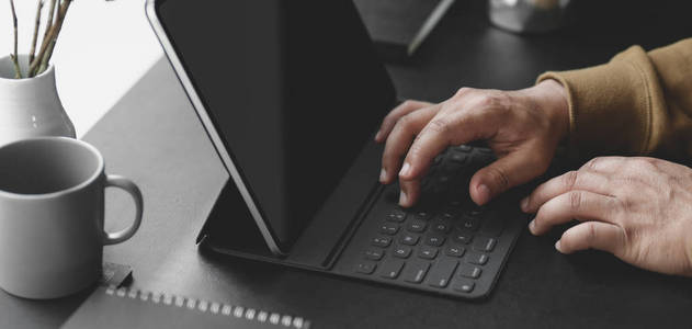 Closeup view of young man typing on keyboard while working on h