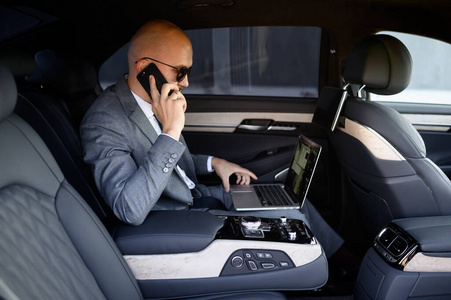 handsome businessman using his mobile phone in a modern car with