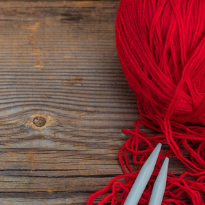 在古老的木质背景上编织棒和红纱。正方形