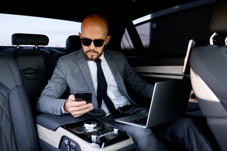 handsome businessman using his mobile phone in a modern car with