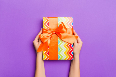 Flat lay of woman hands holding gift wrapped and decorated with 