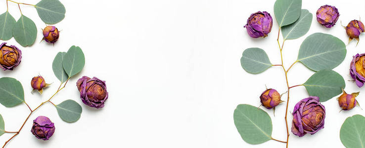 平铺花构图。框架由干玫瑰花和桉树小枝制成，白色背景顶视图复制空间。花卉背景。贺卡设计元素