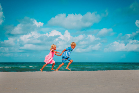 快乐的女孩和男孩在沙滩上奔跑，孩子们在海上享受假期