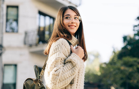 年轻漂亮的女人背着背包在外面摆姿势,在大街上等她的朋友.照片