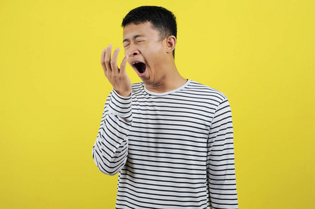 打哈欠亚洲有趣的亚洲男人打哈欠捂住嘴的肖像和表演照片