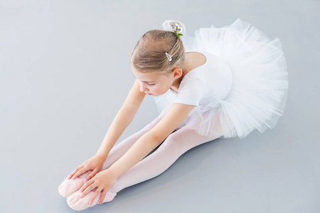 叶子做的裙可爱的小芭蕾舞演员正在灯光下做伸展运动.