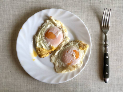白板煎蛋，灰色桌子上。早餐吃炸鸡蛋。美味的蛋黄菜。
