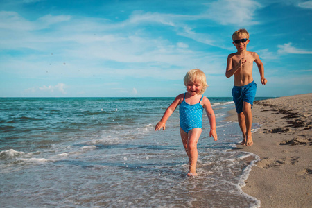 快乐的小女孩和男孩在沙滩上奔跑
